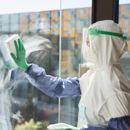 Hazmat worker cleaning window